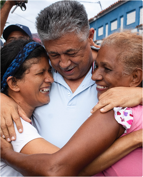 Candidato a la alcaldía abrazando a unas personas en un evento comunitario en Palo Negro.